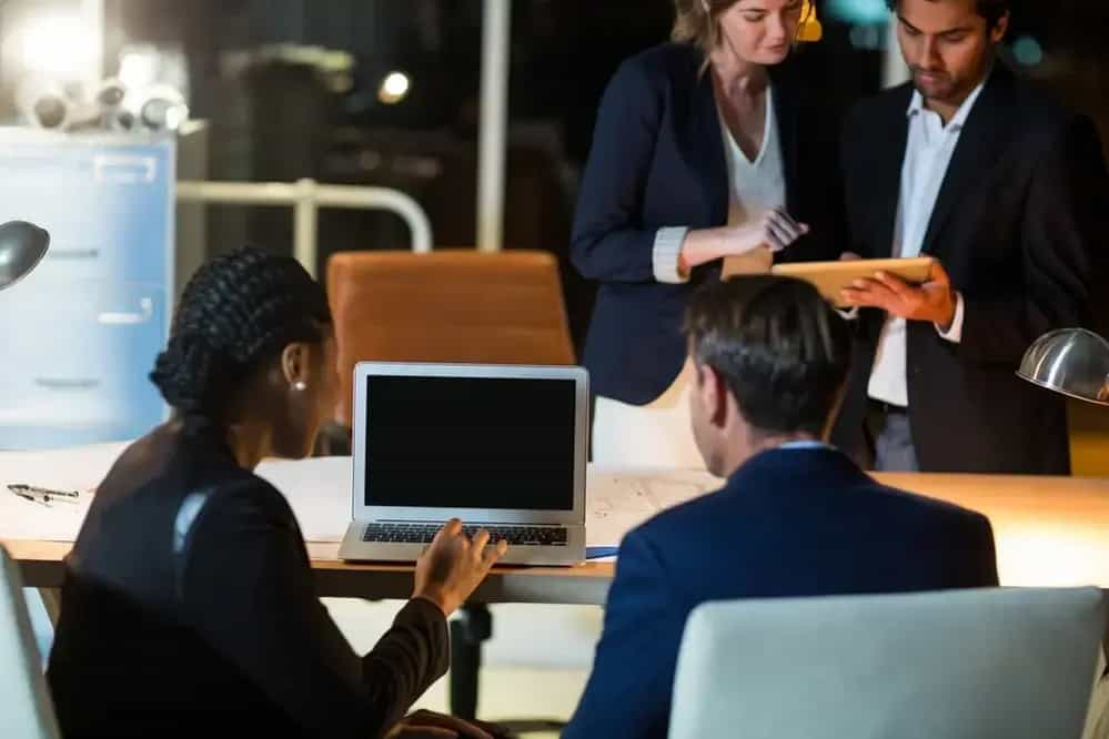 Businesspeople discussing over laptop and digital tablet in office