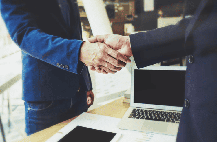 two men shaking hands, wearing suits